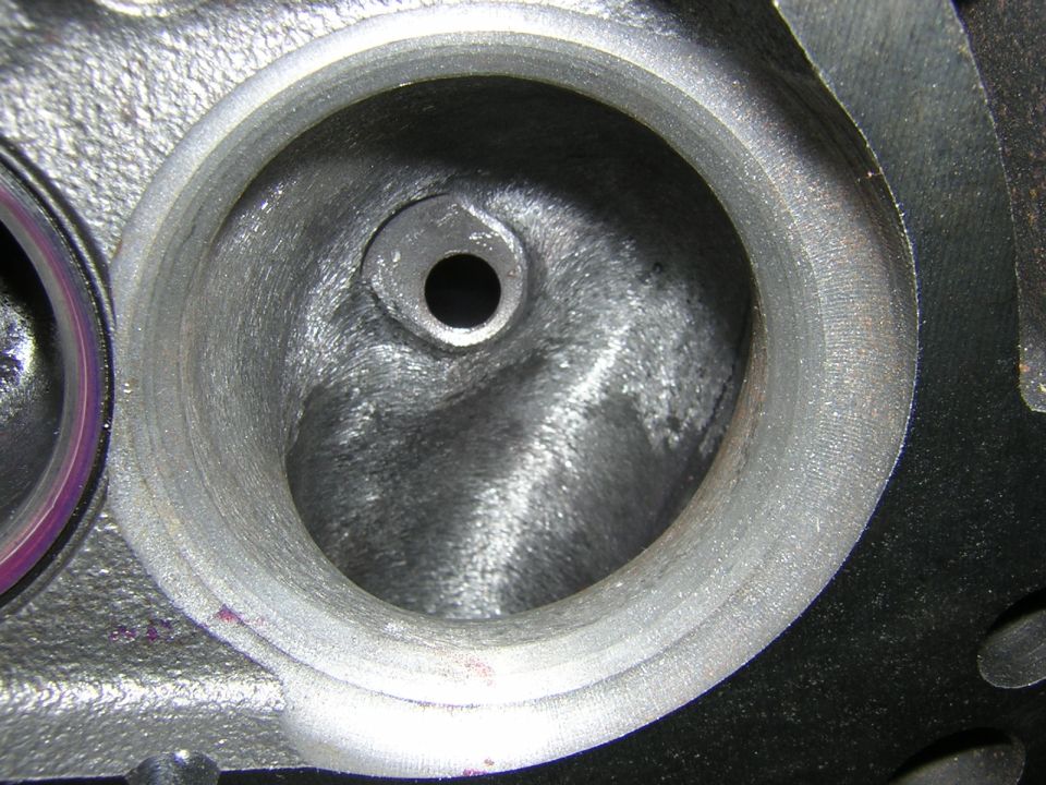 Machined round port in a cast-iron head with a small threaded boss in the port floor