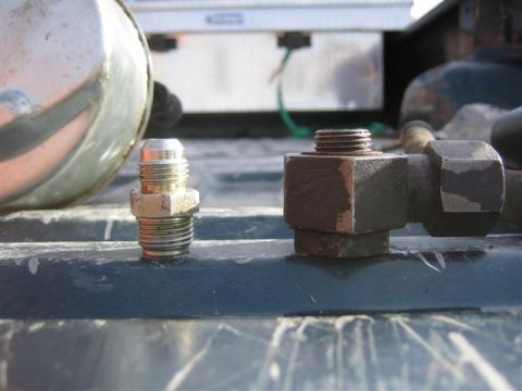 1994 Ford Bronco - Two different metal fittings are shown in detail, resting on a textured surface.