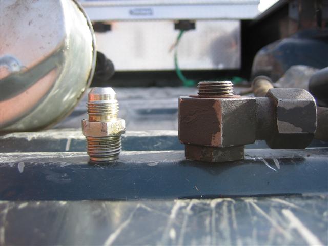 Close-up of two metal fittings, one shiny and one rusty, on a dark surface