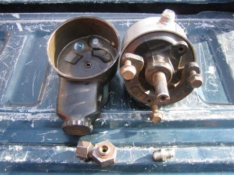 1994 Ford Bronco - Disassembled power steering pump and associated fittings are laid out on a weathered blue surface.