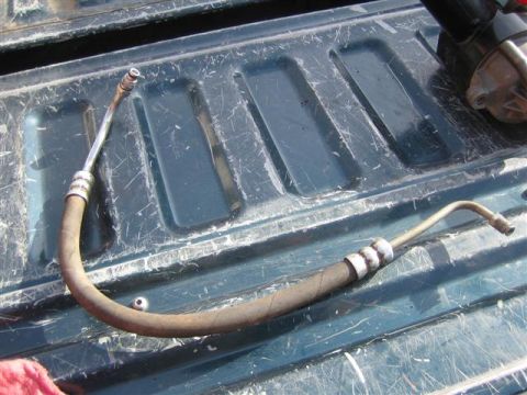 1994 Ford Bronco - A power steering hose lies on a dark green truck bed, with a Supermotors.net logo visible in the lower right corner.