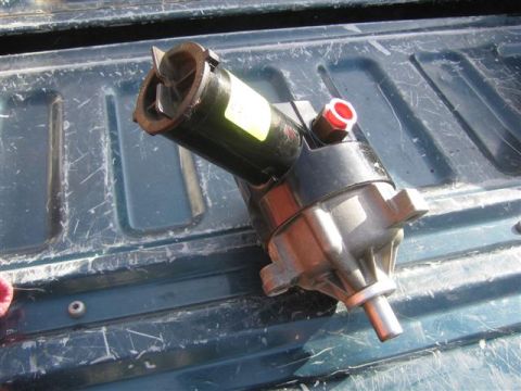 1994 Ford Bronco - A power steering pump is shown resting on a weathered truck bed surface.