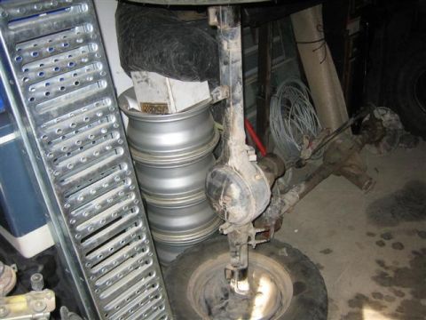 1994 Ford Bronco - Various vehicle parts, including rims and axles, are stored in a garage.