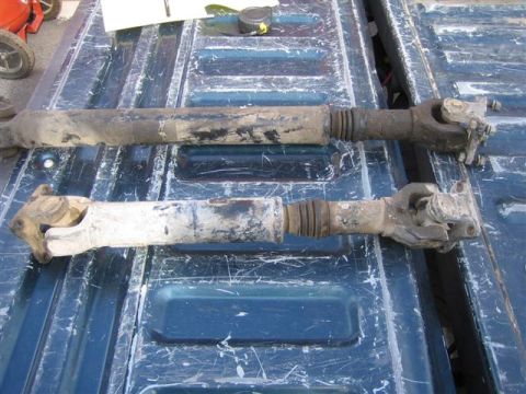 1994 Ford Bronco - Two driveshafts are shown on a blue truck bed, one darker than the other.