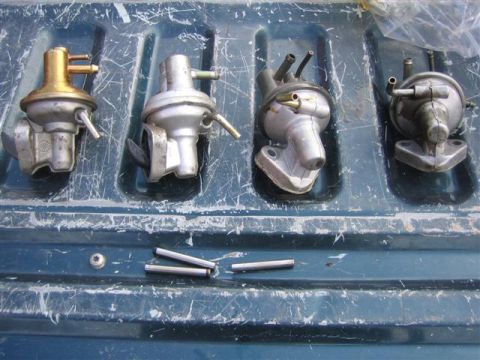 1994 Ford Bronco - A collection of four fuel pumps and several small metal pins are laid out on a blue, scratched surface, possibly a truck bed.