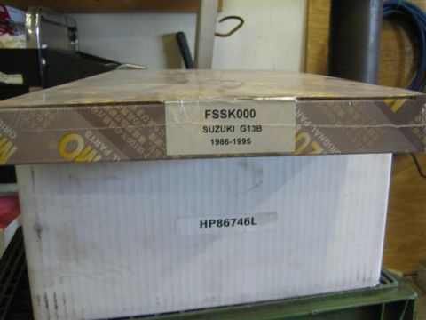 1994 Ford Bronco - A box labeled SUZUKI G13B 1986-1995 sits on top of another box.