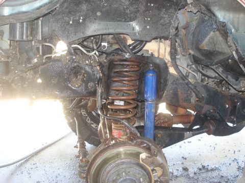1989 Ford Bronco II - The underside of a vehicle shows its suspension system, including the brake assembly and shock absorber.