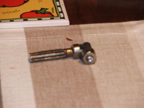 1996 Ford Bronco - A small metal tool with a T-shaped handle and a swiveling head is shown on a striped fabric surface.