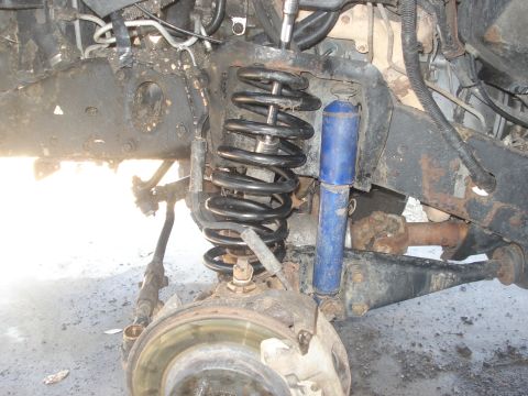 1989 Ford Bronco II - The front suspension system of a vehicle is shown, including the coil spring, shock absorber, and brake rotor.