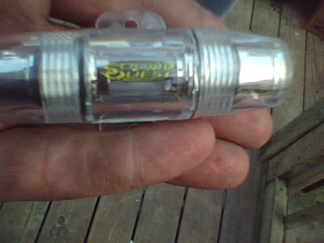 Hand holding a clear in-line fuse holder with a yellow label inside