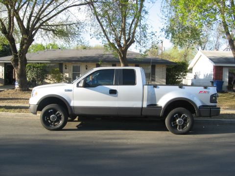 1979 Ford Bronco - Side view of a white pickup truck parked in front of a house.