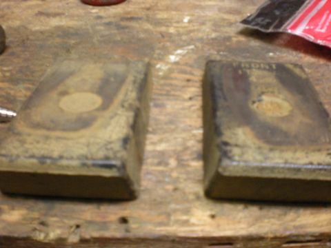 1993 Ford Bronco - Close-up of two brake pads, one marked 'FRONT', resting on a wooden workbench.