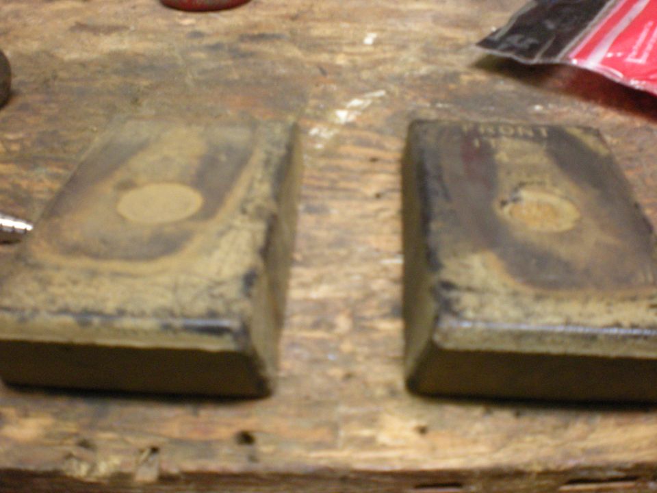Two worn brake pads on a wooden surface. Text on one pad reads 'FRONT'