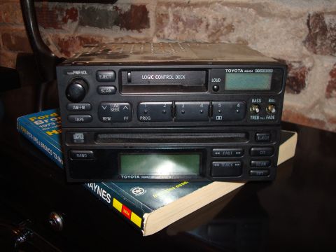 1992 Ford Bronco - A Toyota car stereo and CD player unit are stacked on top of books, one of which is a Ford Bronco repair manual.