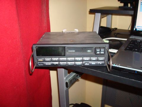1992 Ford Bronco - A Ford car stereo unit is shown on a desk next to a laptop and a red curtain.