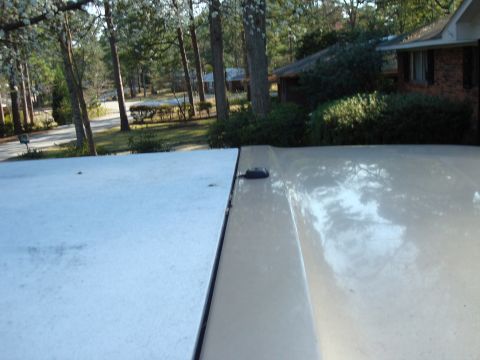 1992 Ford Bronco - The image shows a close-up view of the roofline and rear panel seam of a light-colored SUV, with a residential background.