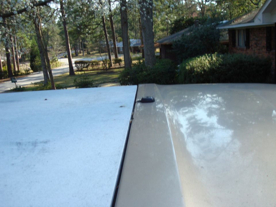 Close-up of a light-colored SUV's roofline and rear panel seam