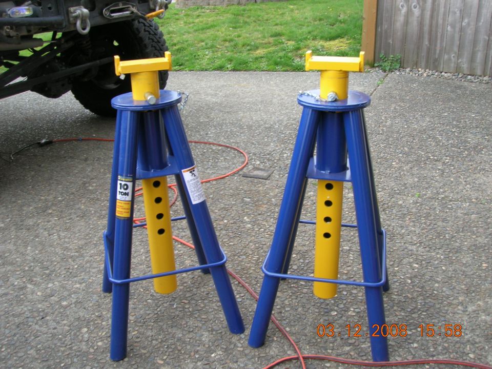 Two blue and yellow 10-ton jack stands on a concrete surface