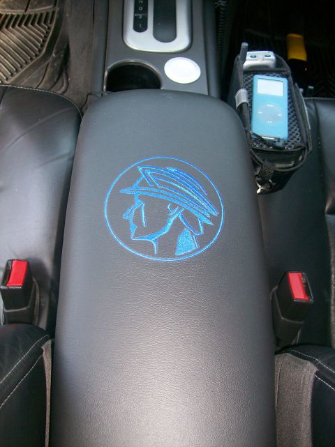 2003 Mercury Marauder - The interior of a vehicle shows a center console with a blue Mercury emblem and an iPod holder attached to the side.