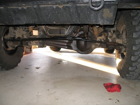 1995 Ford Bronco - The front axle and steering components of a 1995 Ford Bronco are visible from below.