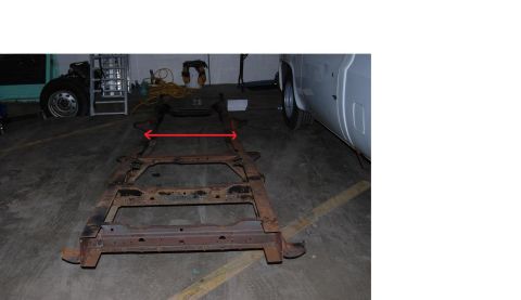1991 Ford Bronco - A vehicle frame is shown on a concrete floor, with red arrows indicating a measurement.