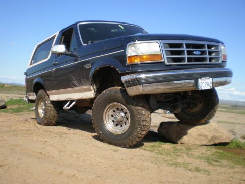 1993 Ford Bronco - This lifted 1993 Ford Bronco is shown off-roading on a dirt path with large rocks.