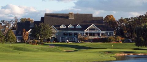 1998 Ford Taurus - A large building sits on a golf course with a pond in the foreground and trees in the background.