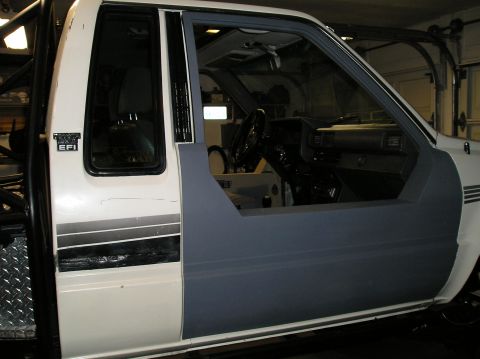 1986 Toyota Hilux - The interior of a pickup truck is visible, with the driver's side door panel removed for work.
