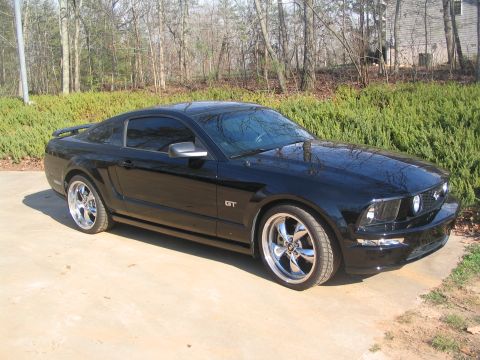 2007 Ford Mustang - Black 2007 Ford Mustang GT with aftermarket wheels parked outdoors.