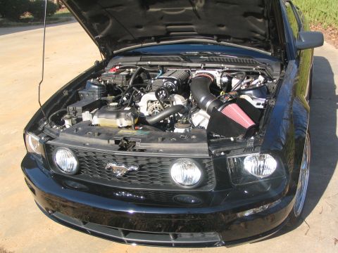 2007 Ford Mustang - Front view of a 2007 Ford Mustang's engine bay, showing a supercharger and custom intake.