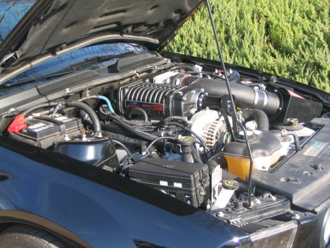 2007 Ford Mustang - The engine bay of a 2007 Ford Mustang shows a prominent supercharger and other engine components.
