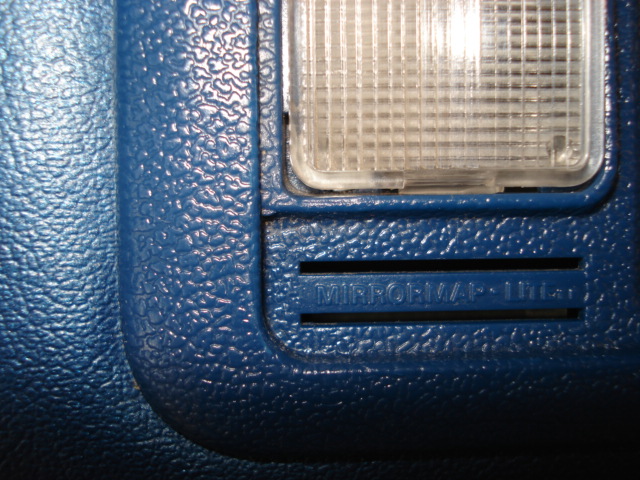 Blue textured plastic interior trim with a light fixture and embossed text 'MIRROR/MAP - ILLUM.'