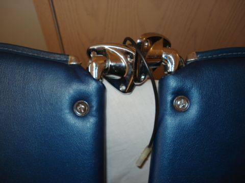 1979 Ford Bronco - A chrome latch with wiring is mounted between two blue upholstered surfaces, likely in a vehicle's interior.