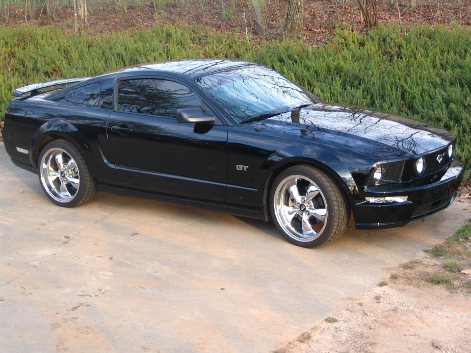 Black 2007 Ford Mustang GT coupe with chrome wheels parked on concrete
