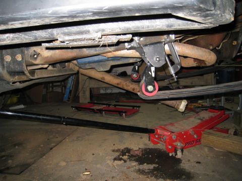 1996 Ford Bronco - Close-up view of a vehicle's undercarriage, showing suspension components and a floor jack.