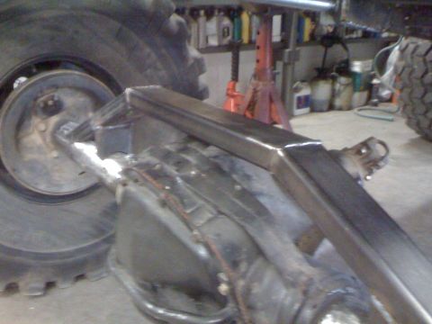 1966 Ford Bronco - Custom suspension fabrication on a vehicle axle, with a large tire in the background.