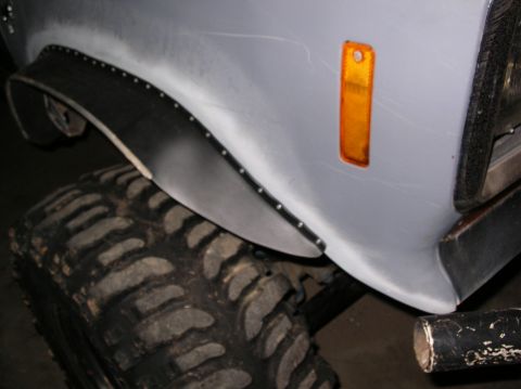 1985 Ford Bronco II - Close-up of a vehicle's fender flare and tire, showing bolted trim and an amber marker light.