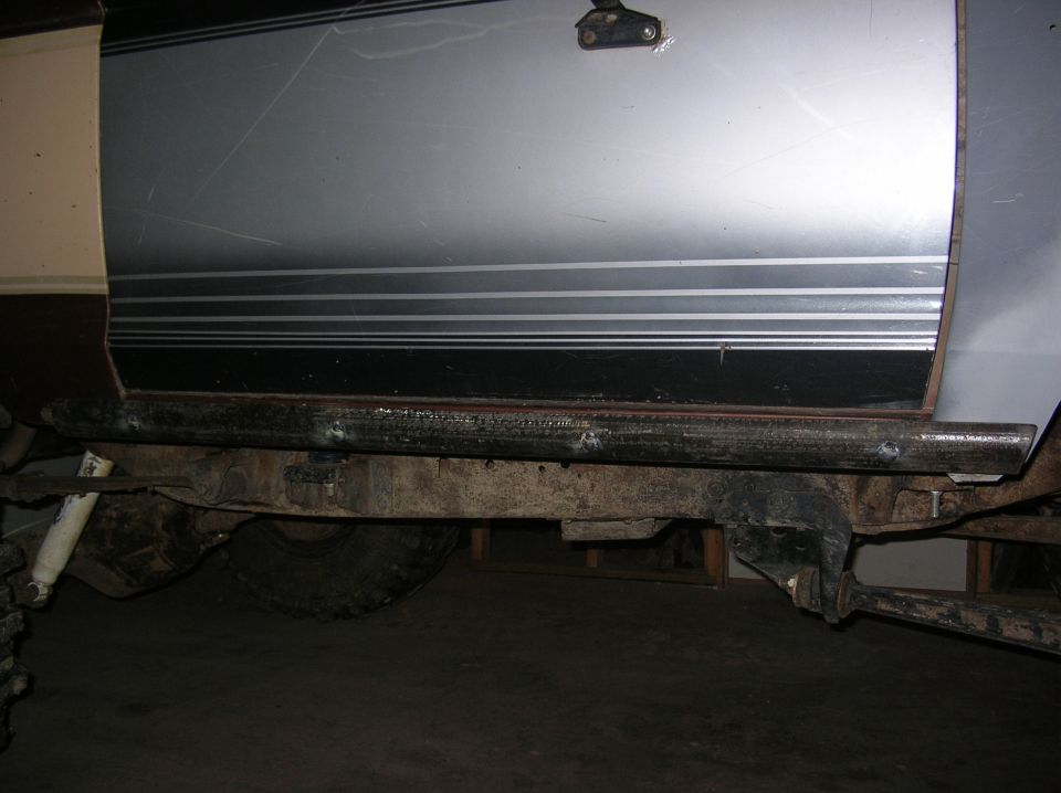 Welded steel rock slider along the rocker of a silver truck with pinstripes in a garage