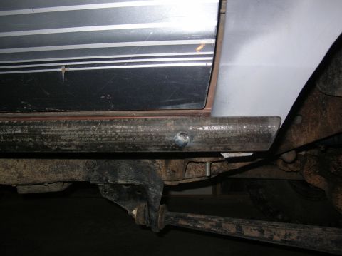 1985 Ford Bronco II - Close-up view of the rocker panel and undercarriage, showing suspension parts and rust.