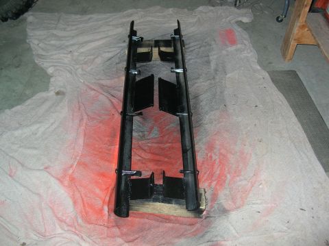 1985 Ford Bronco II - Rocker panels are being painted black, resting on wooden blocks with drop cloths underneath.