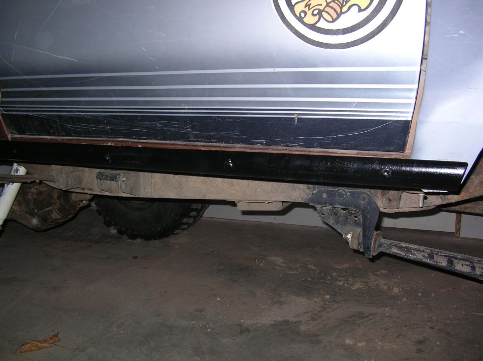Black tube rock slider bolted under rocker panel of a lifted silver truck