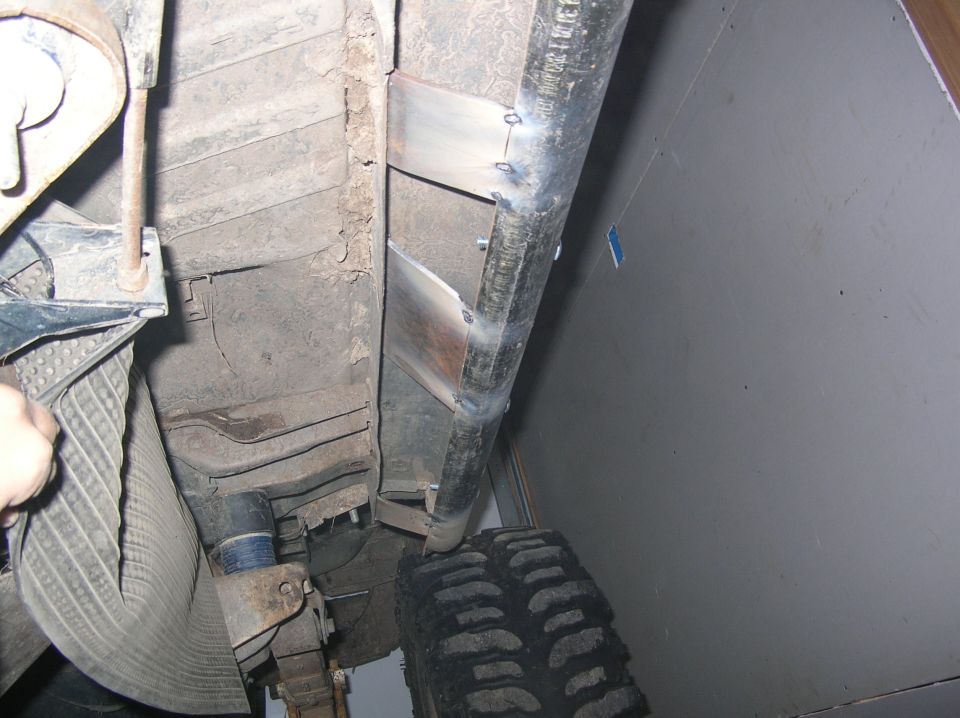 Rock slider tacked to a truck's frame from underneath, bare steel plates and angle iron