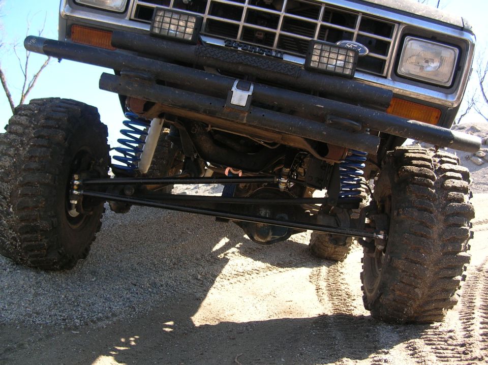 Underside front view of lifted Bronco II showing solid axle, blue coil springs and radius arms