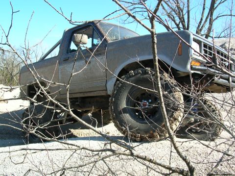 1985 Ford Bronco II - Mud-splattered 1985 Ford Bronco II navigates rough terrain.