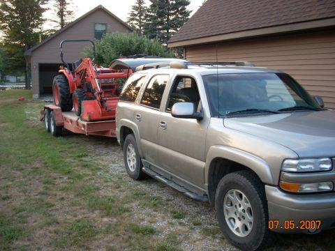 2000 Chevrolet Tahoe - Silver 2000 Chevrolet Tahoe is seen towing a red tractor on a trailer in front of a house.