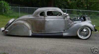 1936 Ford Coupe - A partially finished hot rod coupe sits outdoors, its exposed engine and classic design elements.