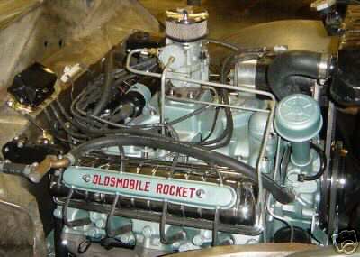 1936 Ford Coupe - Close-up of an Oldsmobile Rocket engine, prominent chrome valve covers with red lettering.