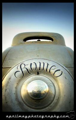 1936 Ford Coupe - A vintage Ford emblem with the name 'Romeo' scripted above it, set against a clear sky.