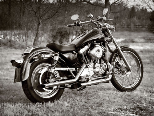 Black-and-white photo of a custom motorcycle parked in a field