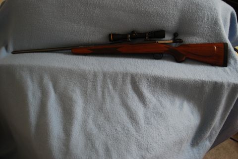 1991 Ford Bronco - A rifle with a wooden stock and a scope is displayed on a blue cloth.